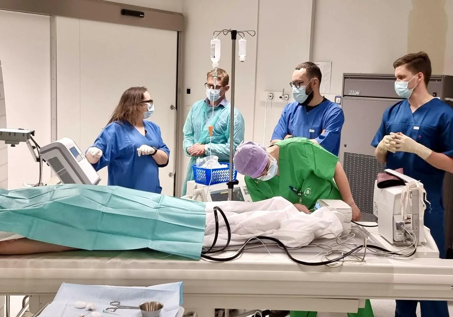 Protseduuri valmistavad ette doktor Martin Reim (paremal). Temast vasakul seisab doktor Donatas Jocius Vilniusest. Tema ees kummargil kliinikumi anestesioloog Neve Vendt. Taga on meditsiinifirmade esindajad, üks Eestist, teine Leedust.